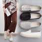 Pair of women's casual slip-on shoes in dark and white, with floral embossed uppers.