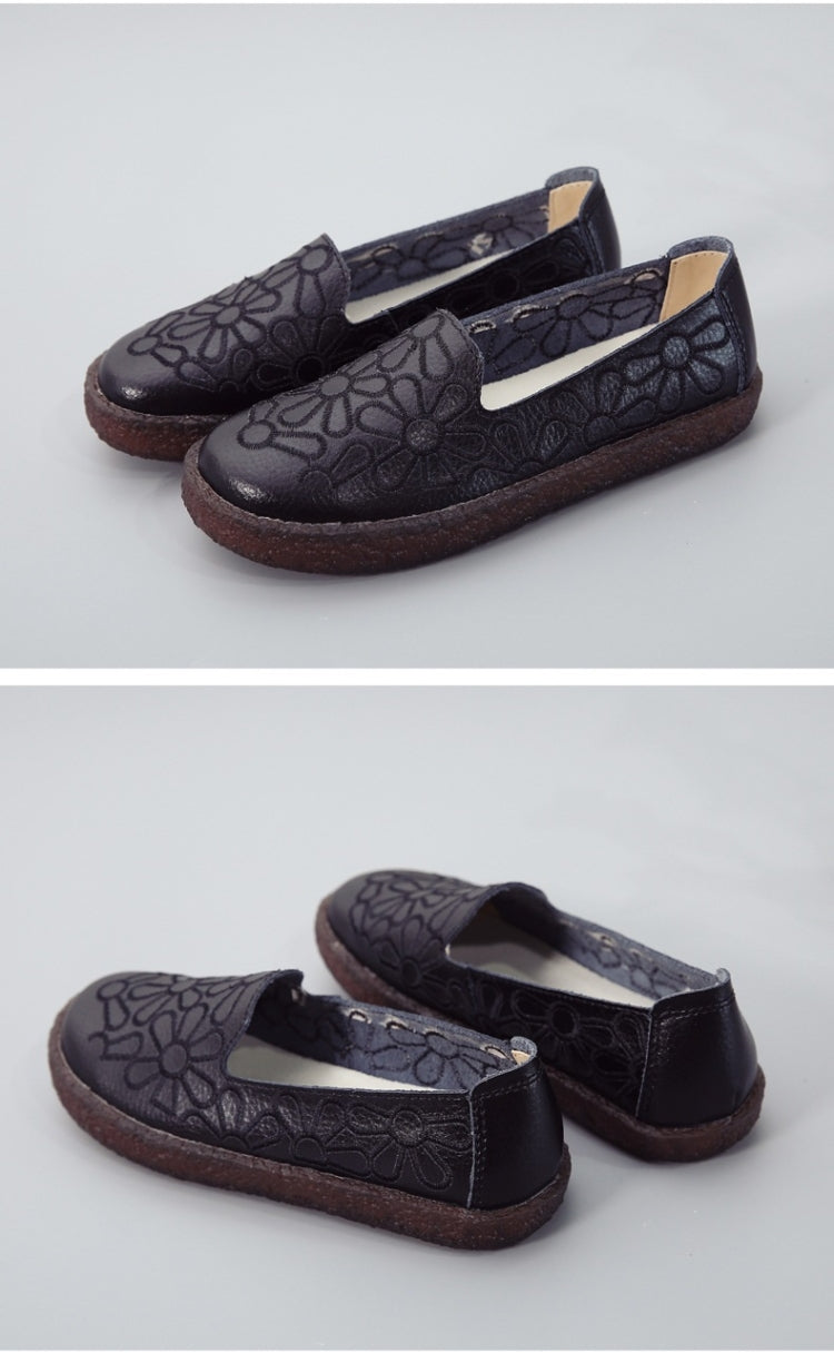 Women's dark embroidered slip-on flats with floral embossed pattern and brown rubber sole.