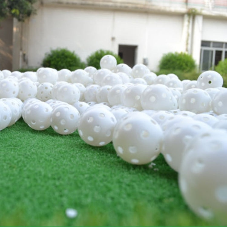 White hollow golf exercise balls, long row of perforated balls outdoors