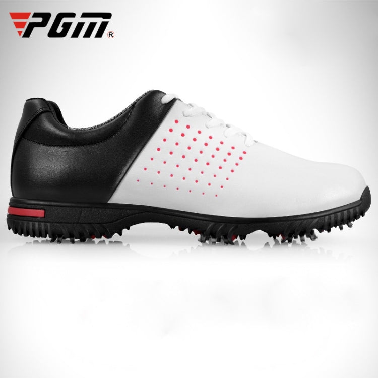 Men's black-and-white golf sneakers with red dotted accents and studded bottom for traction.