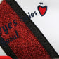 Close-up of white sneaker panel with red glitter text and red heart patch