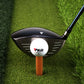 Amber rubber golf tendon tee holding a white golf ball on a round base