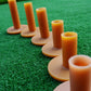Row of amber rubber golf tendon tees on turf, each with round base and peg