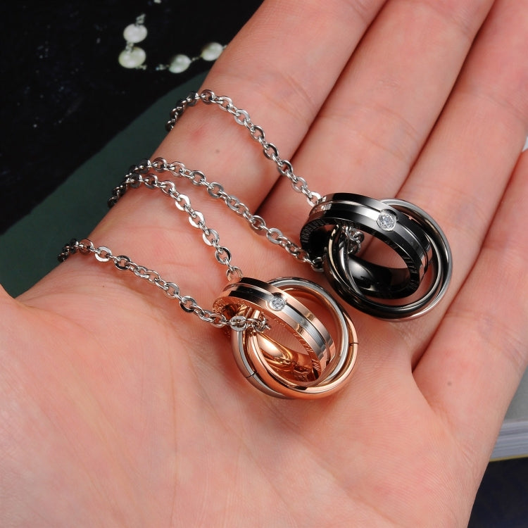 Rose gold and black interlocking ring couple necklaces held in open palm with chains