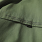 Olive green jacket zipper close-up with black pull tab