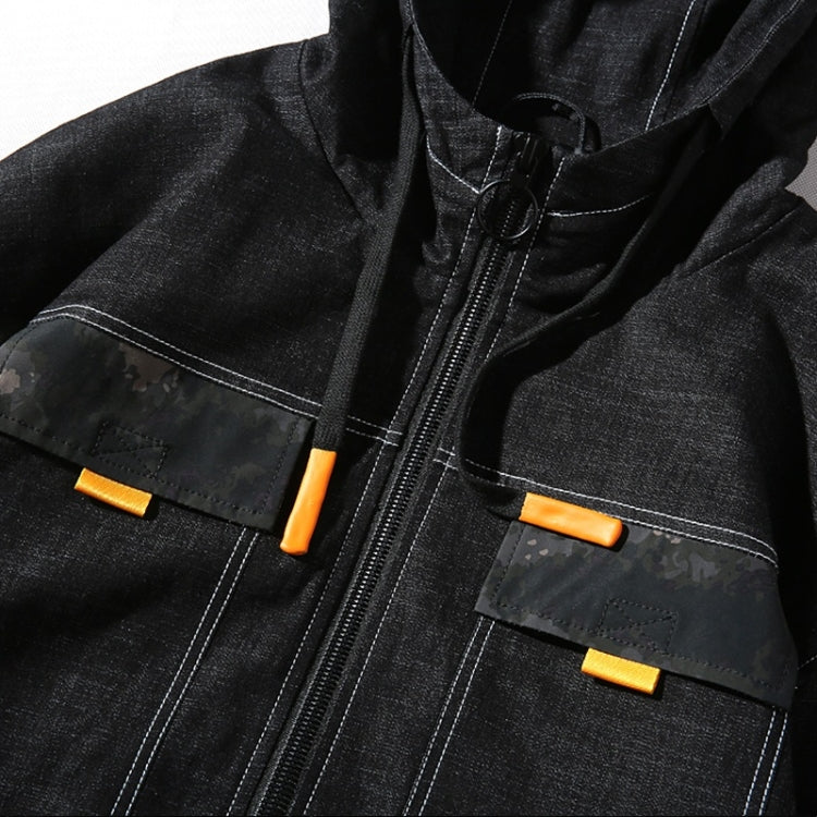 Close-up of black denim jacket front: orange zip, hood, and flap pockets