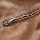 Tan leather jacket close-up of silver zipper pull and stitched seam