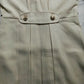 Light beige trench jacket front detail with snap buttons and pleated panel