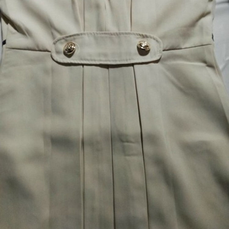 Light beige trench jacket front detail with snap buttons and pleated panel